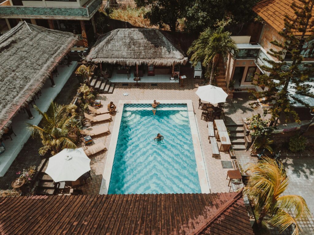 Aerial view of a luxury resort pool surrounded by villas and palm trees.